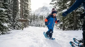 Educational illustration of children snowshoeing near animal tracks, like a snowshoe hare, in a Canadian provincial park.