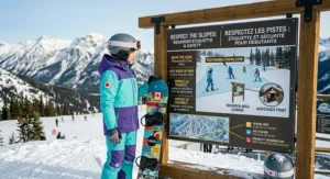 A high-definition photograph capturing an 11-year-old Canadian girl wearing technical snow gear and a CSA helmet, riding a 'CANADA BEGINNER' snowboard down a beginner slope at a resort in the Canadian Rockies.