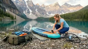 Durable inflatable paddle board package being set up on a shore.