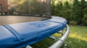 Thick protective foam padding covering the springs on a backyard trampoline with safety net.