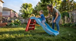 A parent supervising closely as a young child climbs a safe backyard slide for toddlers.