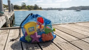 A mesh beach toy storage bag holding a complete beach toy set for kids after a day by the water.