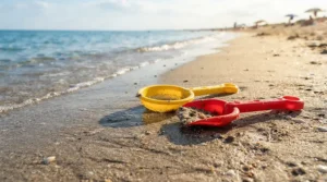 Toddlers safely playing with a lightweight beach toy set for kids on a sandy ocean shore.