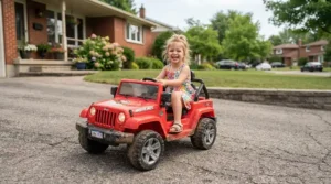 A smiling child cruising in an electric ride-on car on a sunny suburban driveway in Canada.